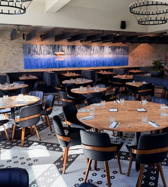 Event seating layout facing a panoramic blue and white snowy forest wall mural under modern round chandelier lighting.